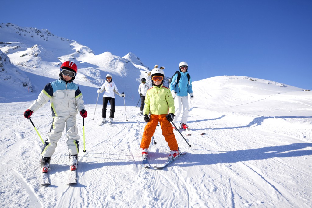 children and adults skiing on flat slope on sunny winter day in the mountains