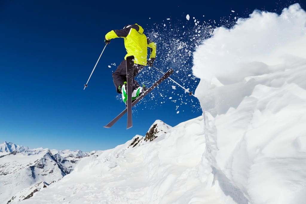 Alpine skier skiing downhill, blue sky on background