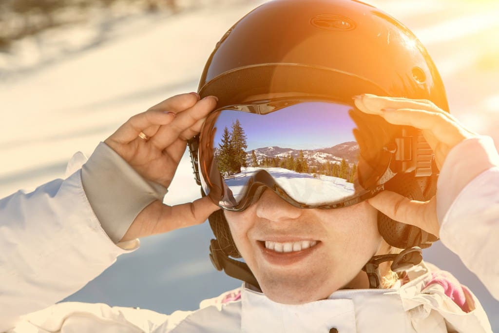 Woman wearing a helmet and glasses on the background of snow win