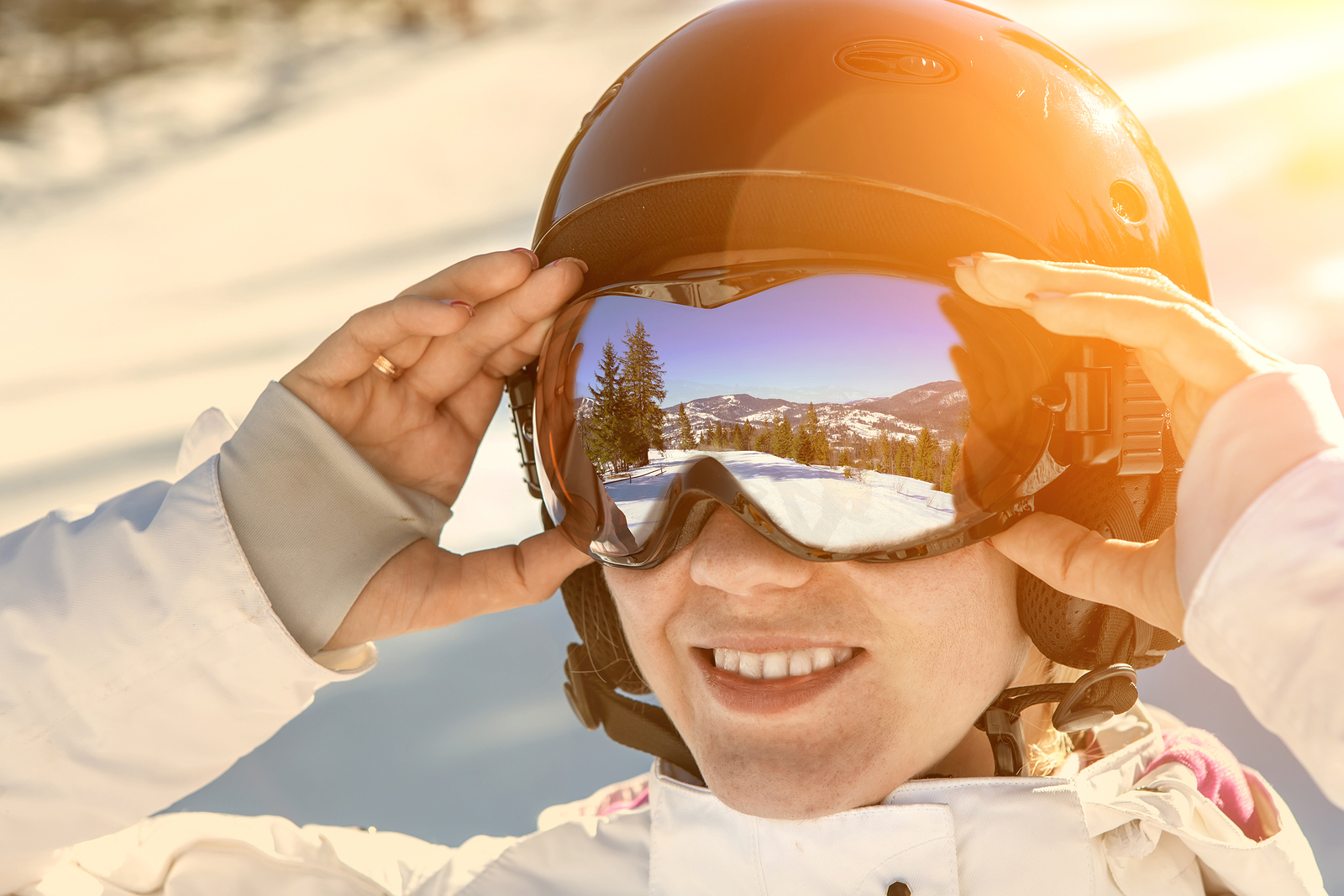 Woman wearing a helmet and glasses on the background of snow