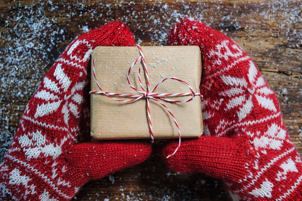 Female hands in winter gloves with christmas gift box