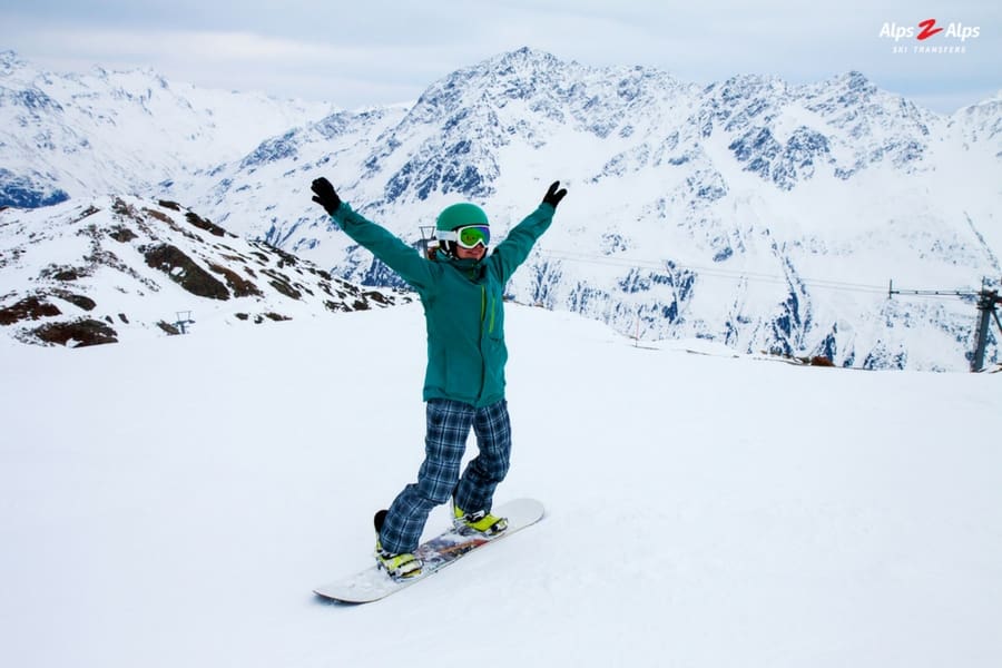 Happy woman learning to snowboard on the mountain