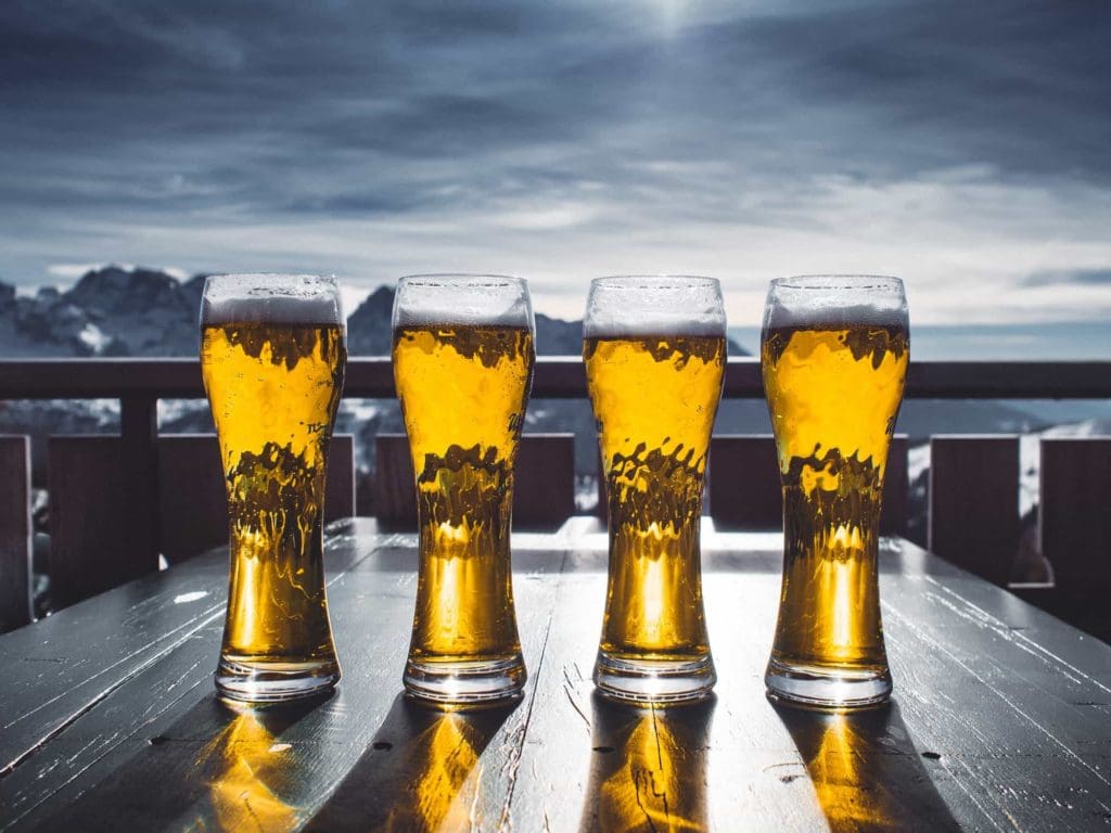 Apres ski beers lined up on a table with mountains behind