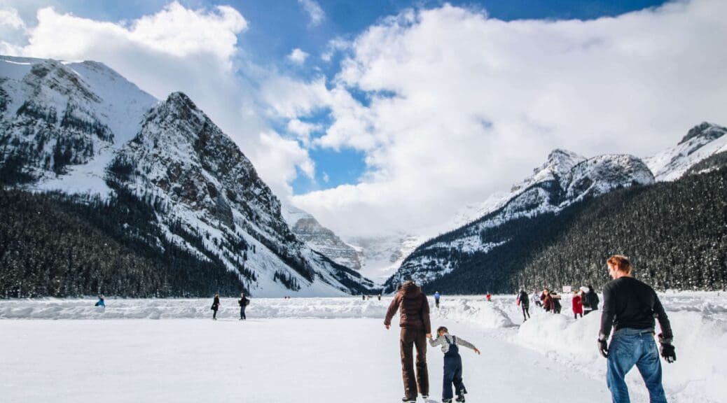 Families ice skating with mountains in the background