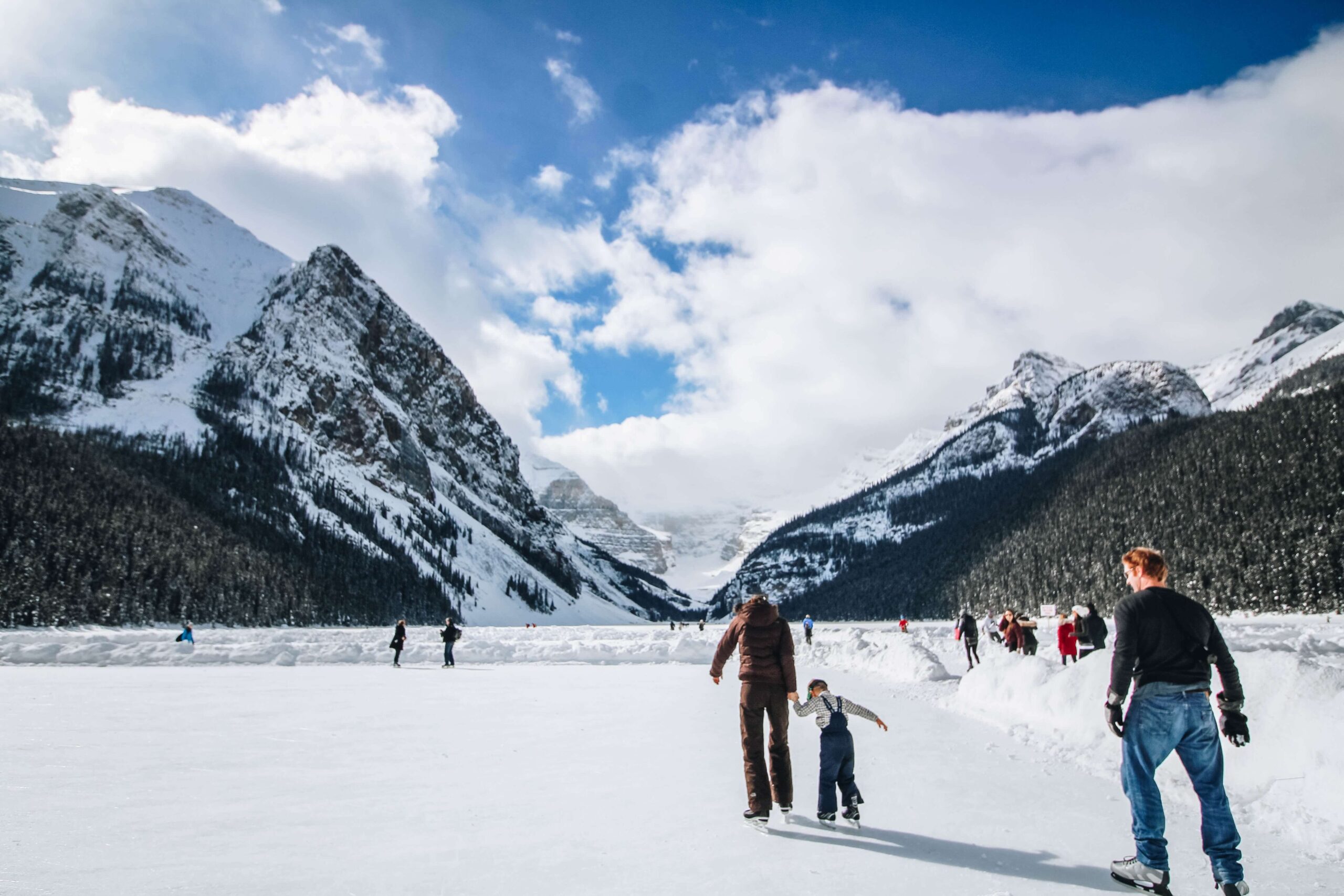 Families ice skating with mountains in the background