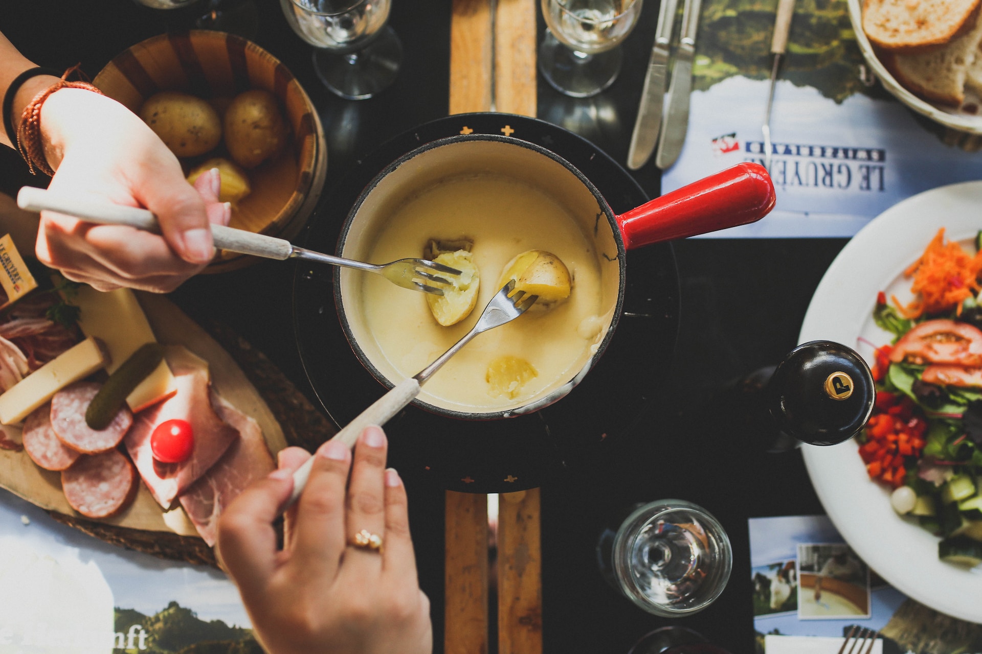 hands dipping potatoes into cheese fondue