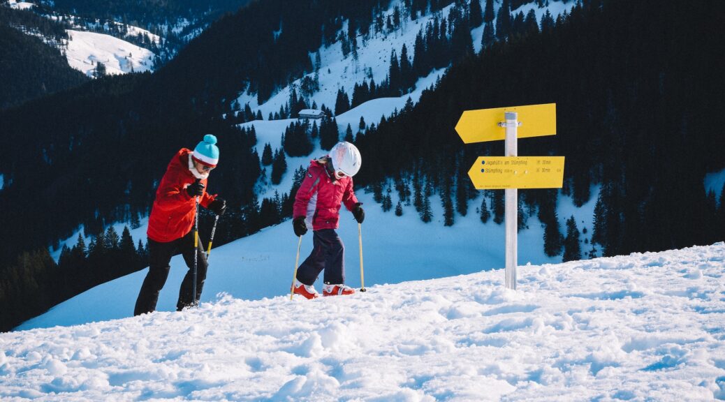 parent and child walking up mountain on skis