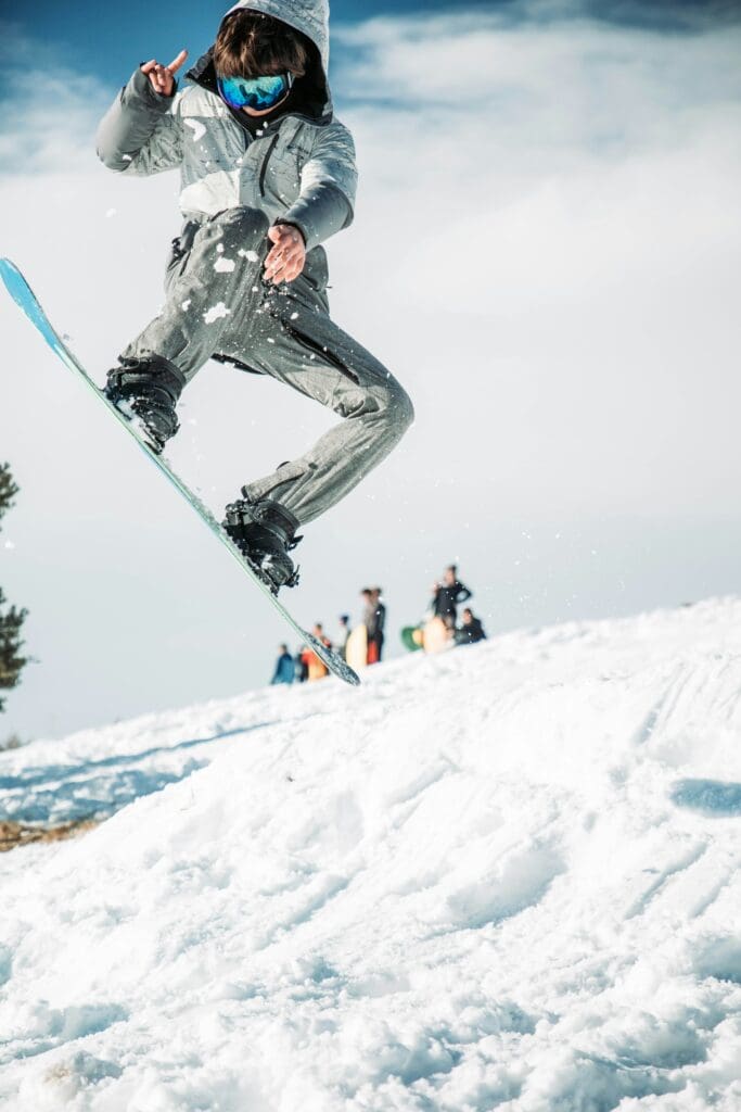 boy doing a jumping trick while snowboarding